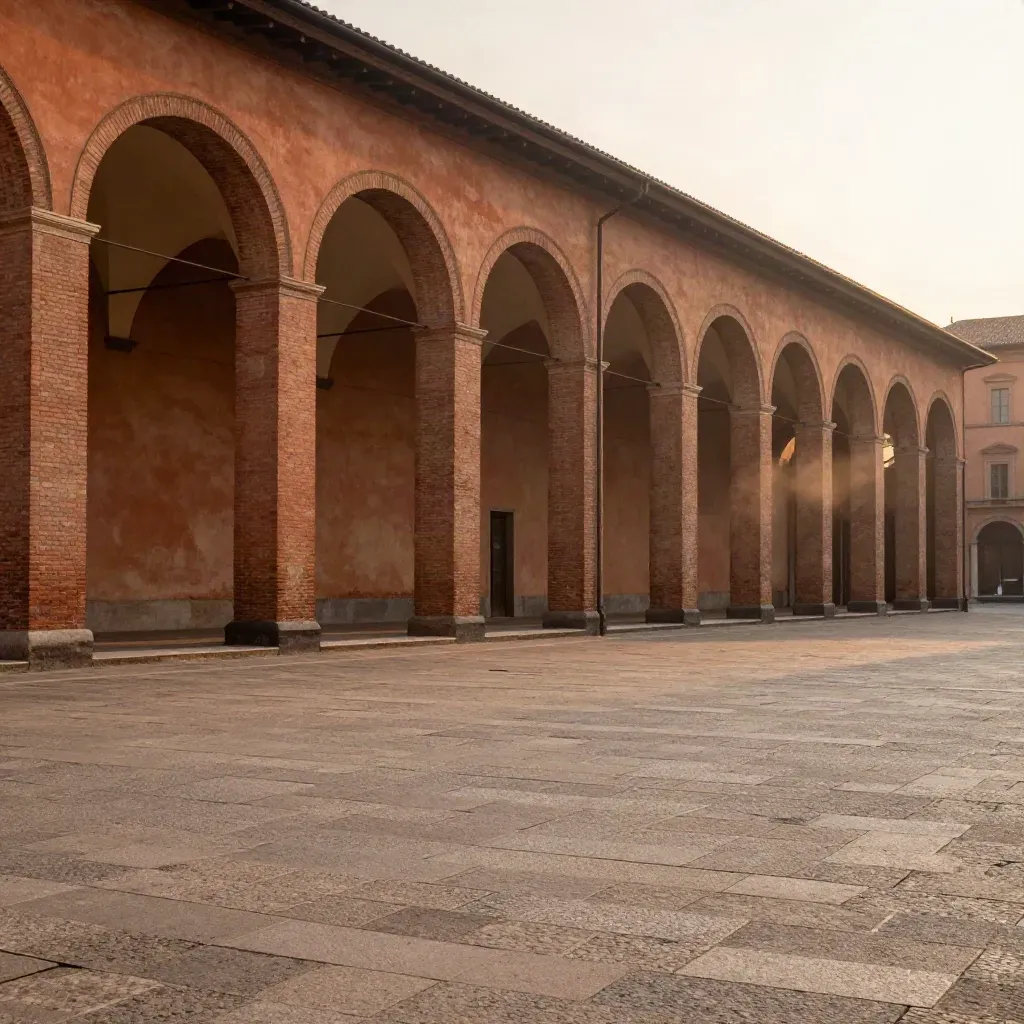 Portici di Bologna al tramonto con piazza vuota e luce calda.